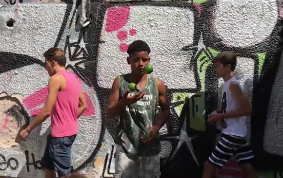 Jonglierender Junge steht vor Graffiti Wand